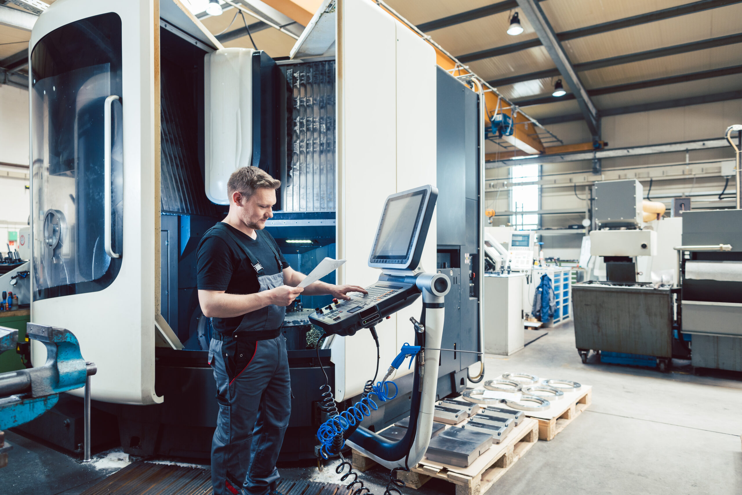 Worker in metal industry operating a modern cnc machine