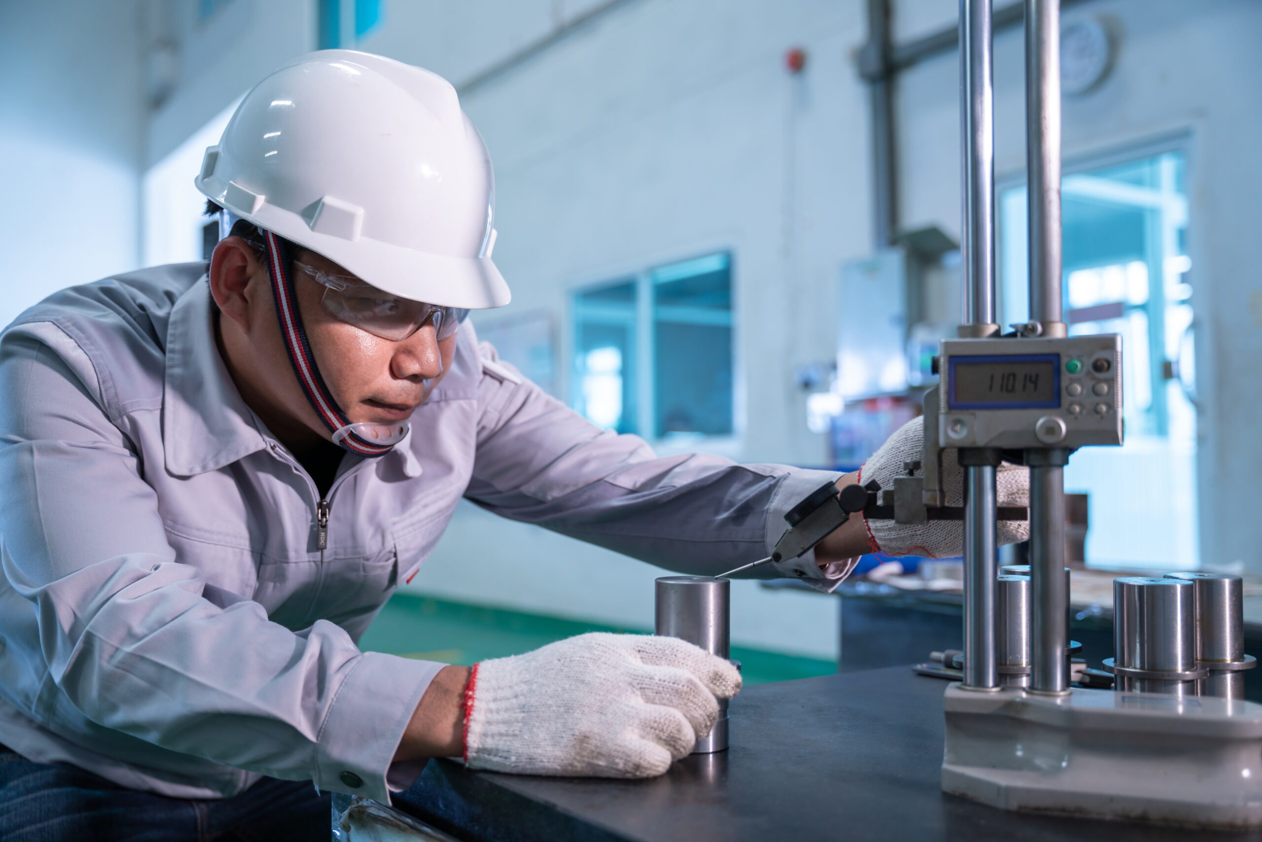 Asian technician worker wearing a safety suit and Quality Checking with hight gauge mass Product on Granite Surface Plate in industrial factory.